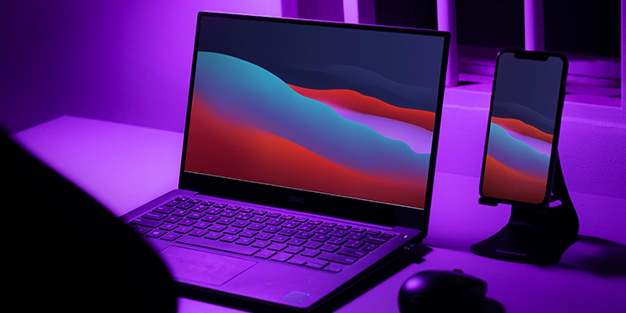 laptop on desk with purple background