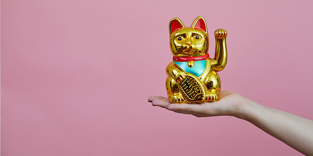 Golden toy cat waving with pink background