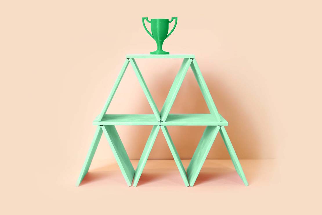 Green trophy on top of green cards on beige background